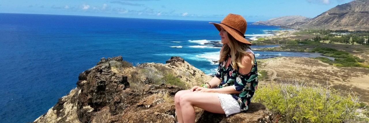 When Your Life's Timeline Is Interrupted by Illness A photo of the writer at the beach, sitting on rocks and watching the waves.
