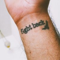 Tattoo on a wrist that reads "Fight back"