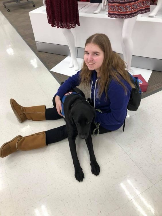 woman sitting on floor of store with service dog