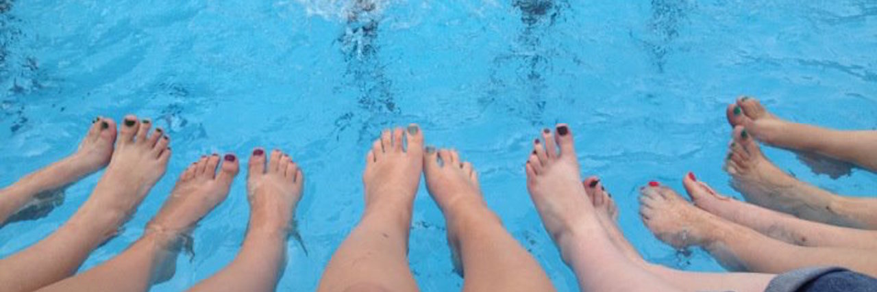 four pairs of legs dangling in pool