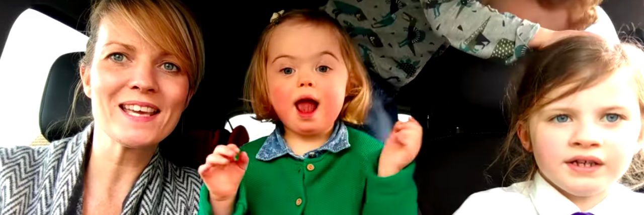 What to Know About the Video: '50 Mums | 50 Kids | 1 Extra Chromosome' Screen shot of little girl with Down syndrome in car with mom and two siblings singing