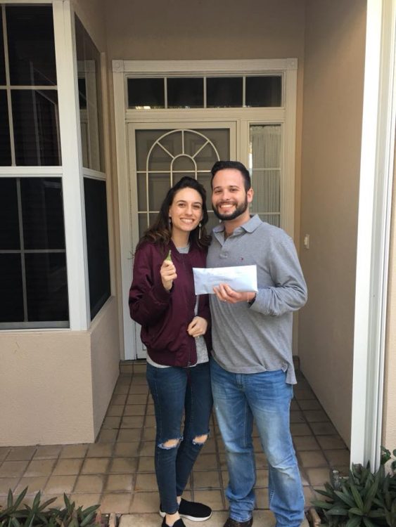 woman and her husband standing on the front porch of their new home holding their keys