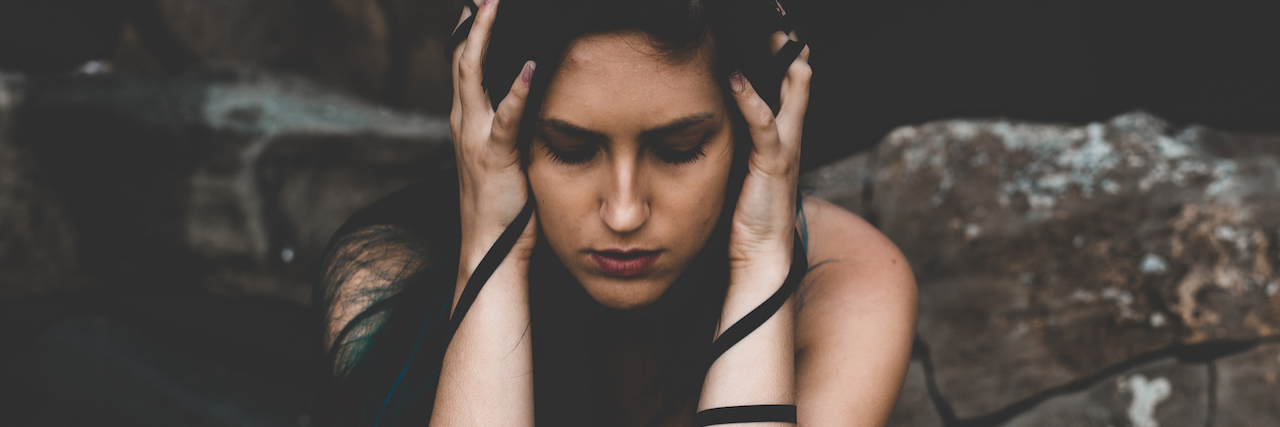 Why You Don’t Have to Be a Mental Health Advocate The author with her hands over her eyes, kneeling outside next to rocks
