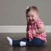 Baby girl with Down syndrome sitting on floor smiling at camera