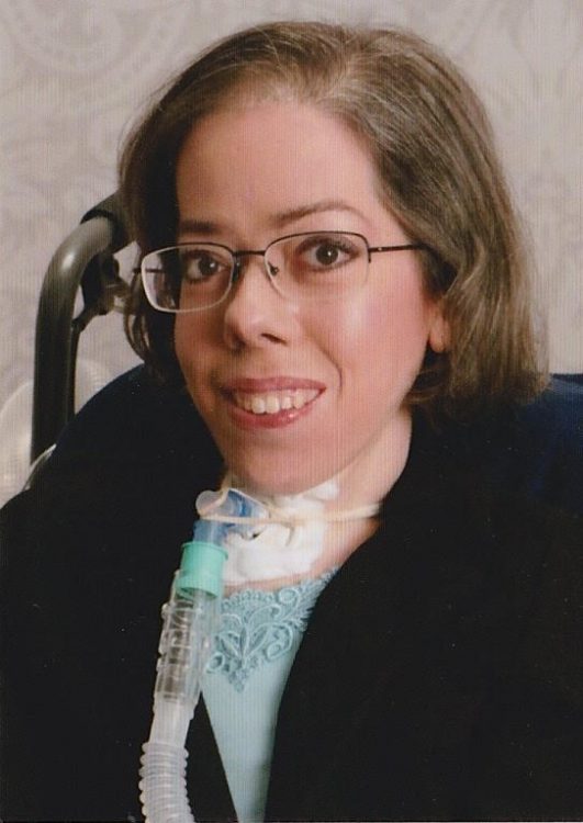 A woman with a breathing assistive device smiling