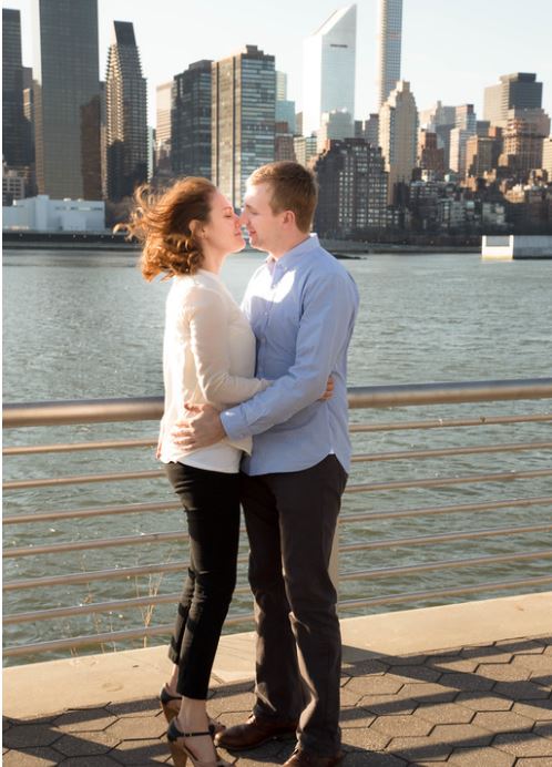 couple standing on a bridge kissing after getting engaged