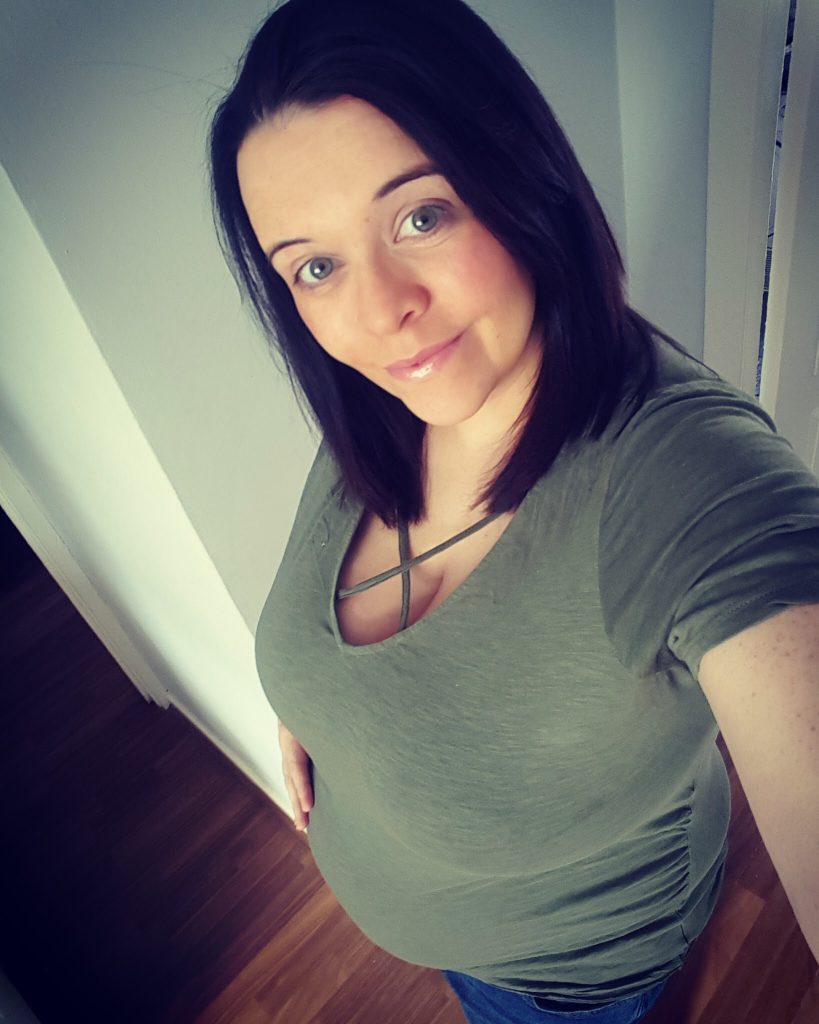 woman taking a selfie and showing off her pregnant belly