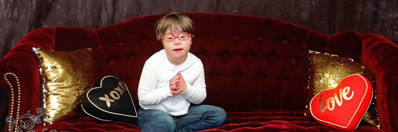 I Believe Down Syndrome Day Is for Everyone Boy with Down syndrome sitting on couch