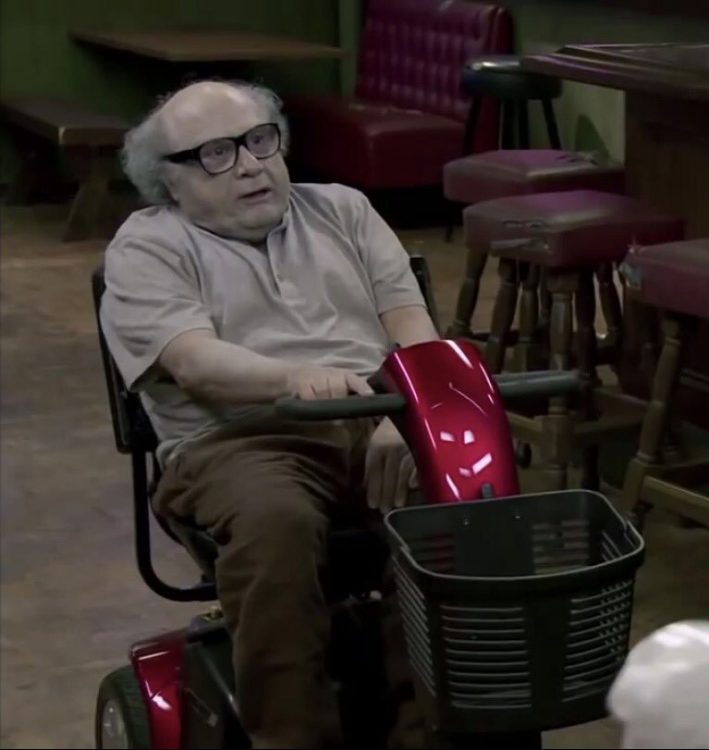 danny devito sitting in a motorized scooter and looking extremely pale