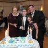 mother, father, daughter and son at the son's bar mitzvah standing in front of a cake