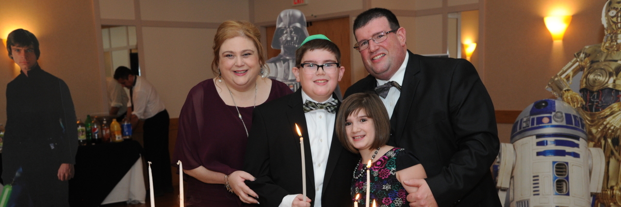 Backing Out of an Event at the Last Minute Due to Chronic Illness mother, father, daughter and son at the son's bar mitzvah standing in front of a cake