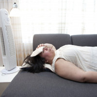 person sleeping with an ice pack on their head and a fan