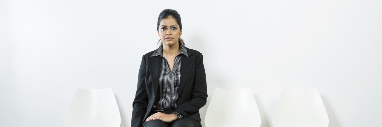 Anxious Indian woman waiting for a job interview while sitting on a row of chairs