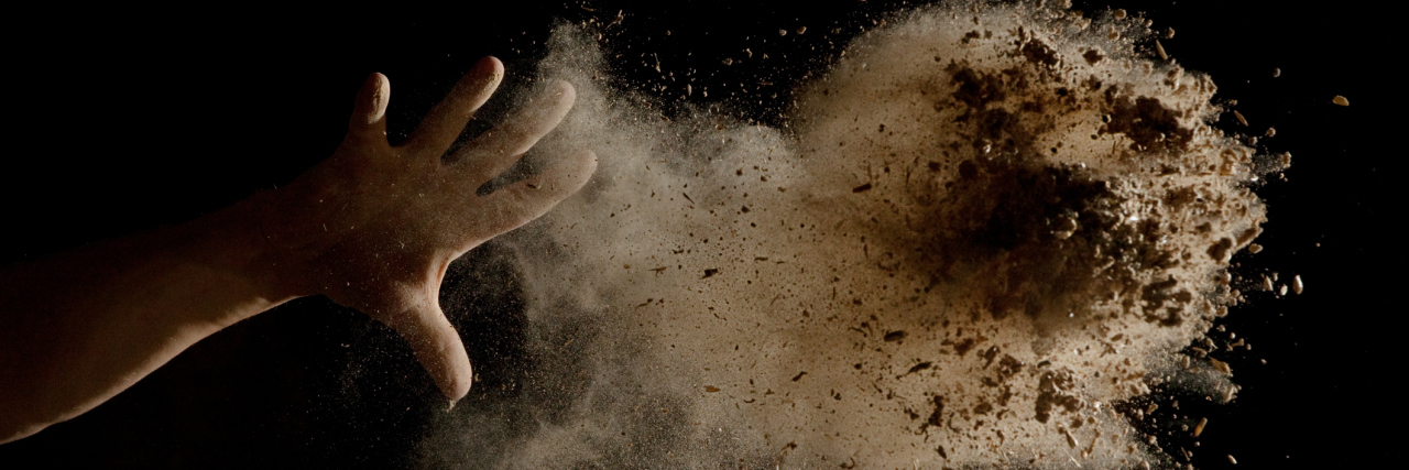 A hand throwing dirt in the air.