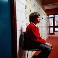 A boy sitting outside of a classroom