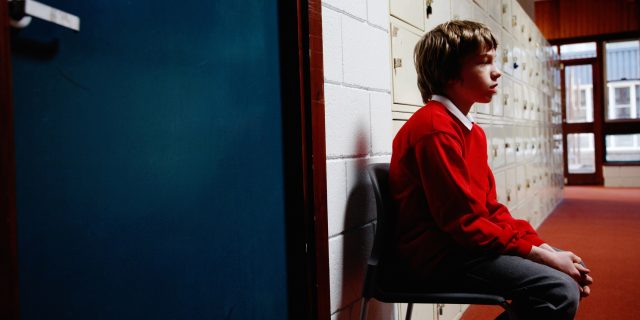 A boy sitting outside of a classroom