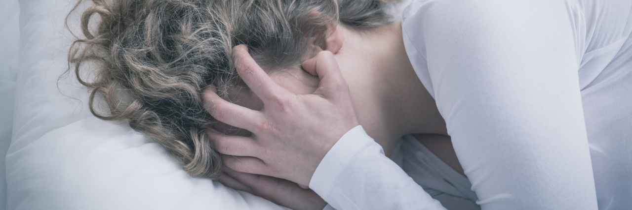 What It's Like to Be Dissociated While Having a Panic Attack close up of young woman crying in despair covering face