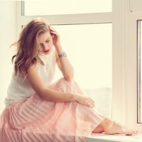 A woman with a serious expression sitting by a window.