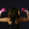 back view of a female boxer flexing her biceps and wearing pink boxing gloves