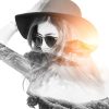 double exposure of a woman wearing a hat and sunglasses and a sunny mountain range