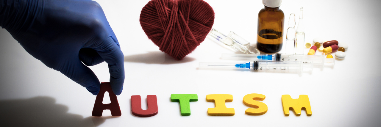 Balovaptan Drug Designed to Help Autistic People With Social Skills Hand and autism word on the white background with injections and pills in the background.