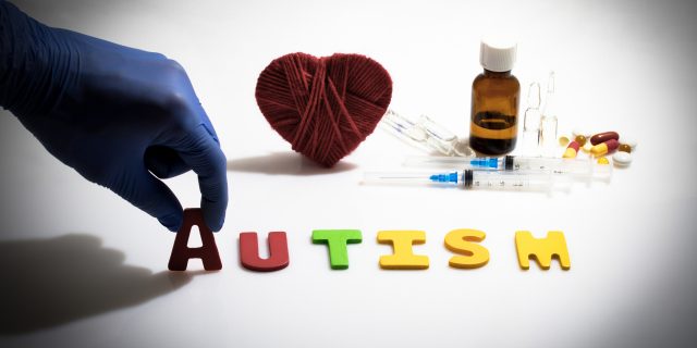 A New Drug Designed to Help Autistic People With Social Skills Is Currently in Clinical Trial Hand and autism word on the white background with injections and pills in the background.