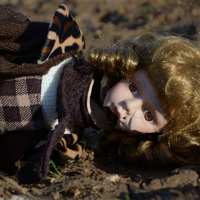 broken porcelain doll lying on ground abandoned