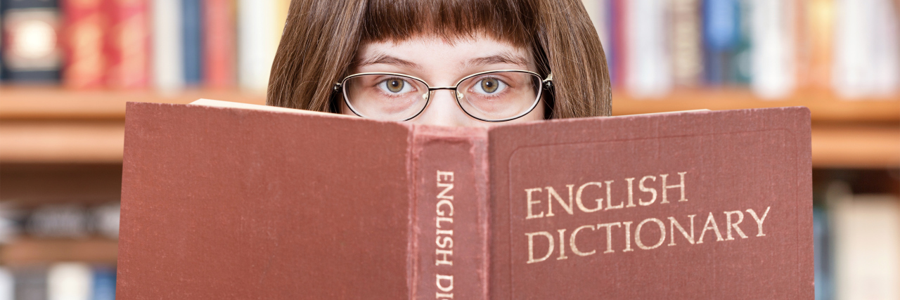 Woman looks over English dictionary.