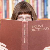 Woman looks over English dictionary.