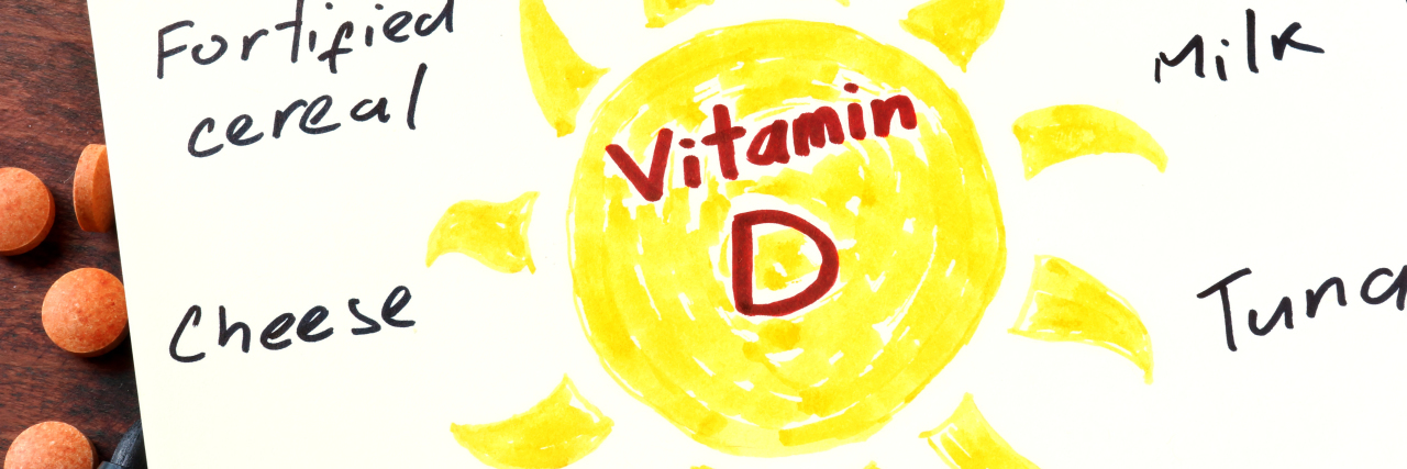 Vitamin D Deficiency and Cerebral Palsy Notepad with vitamin D and pills on the table.
