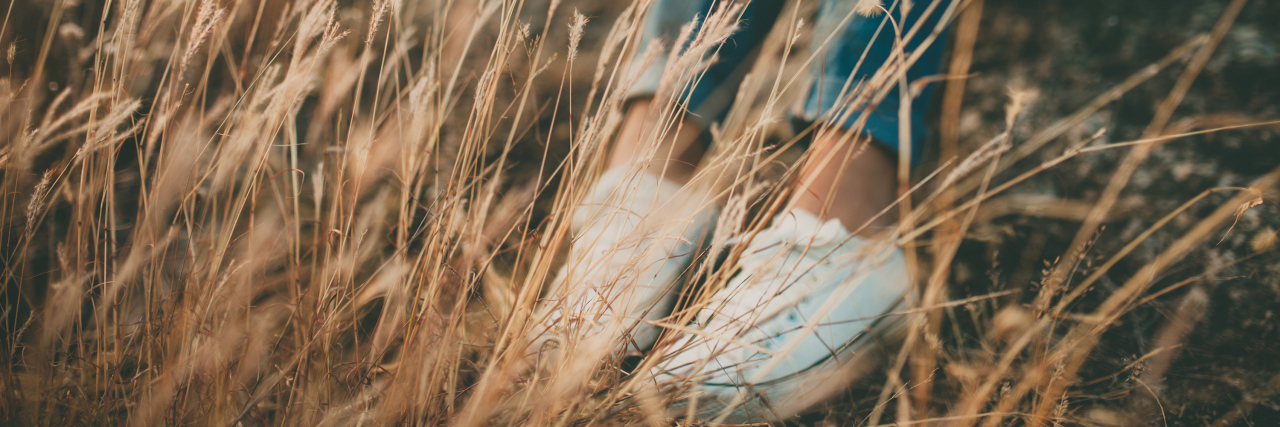 How My Illness Gave a Whole New Meaning to the Word 'Lonely' A picture of a woman sitting alone in a field.