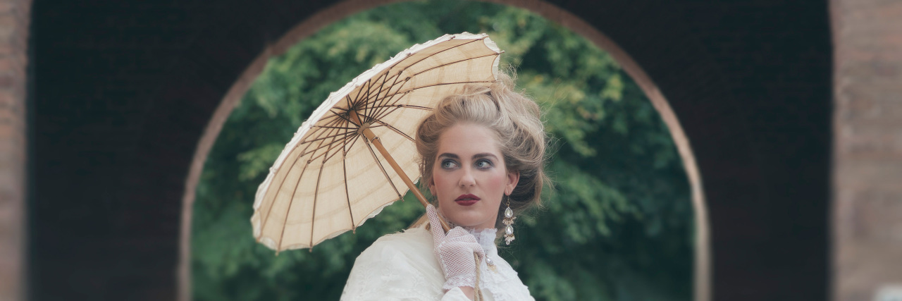I'm Allergic to the Sun, but I'm Not a Delicate Flower. I'm a Warrior. Victorian fashion girl with umbrella standing in front of gate.