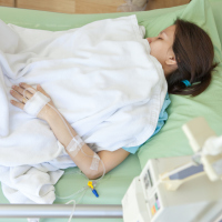 A woman in a hospital bed with an IV in arm.