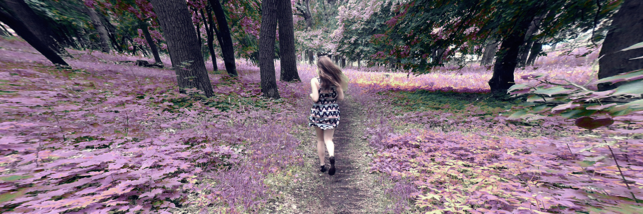 Blurred motion abstract image of a young woman traveling away from the camera. The girl travels down a path that has purple leaves growing on either side of it. She moves toward a forest with green trees. The trunks of the trees are curved unnaturally and appear warped.