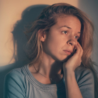 Woman alone and depressed in sunset light.