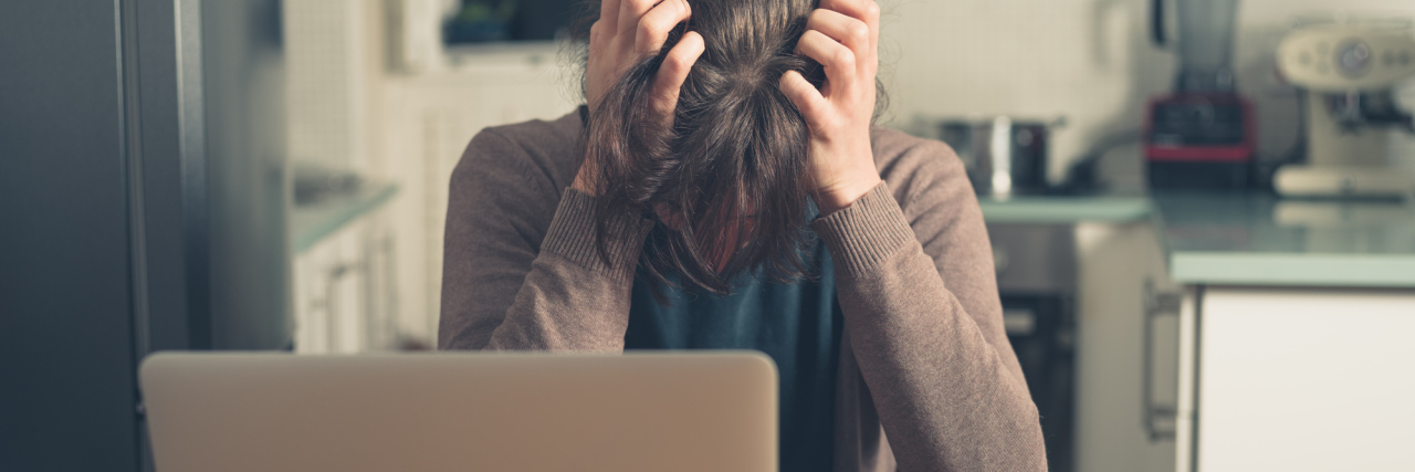 upset young woman in front of laptop pulling hair