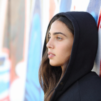 Profile portrait of a skater style teenager girl with an unfocused graffiti wall in the background