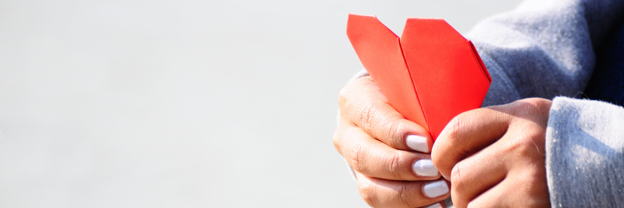 Experiencing the Loss of Siblings Due to a Congenital Heart Defect Hands Holding a Red Heart-Shaped Paper