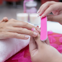 close up of woman receiving manicure from beautician at nail salon