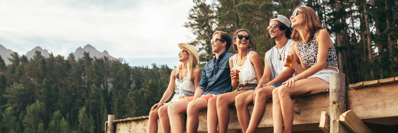 The Types of People You Meet When You Have a Chronic Illness group of friends sitting on the edge of a dock on a lake