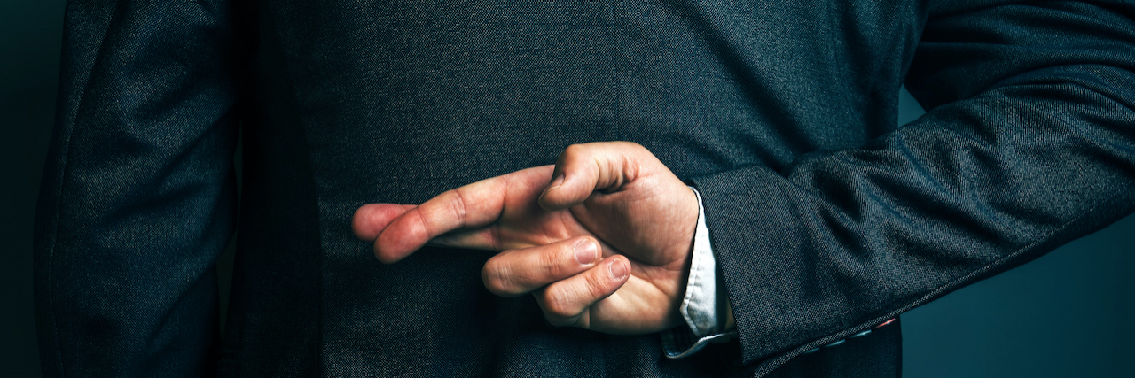 13 Lies People With Depression Tell A man crossing his fingers behind his back.