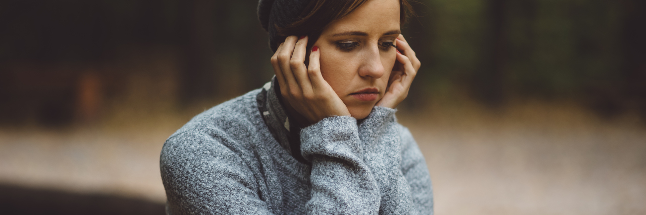 Why I Can’t Just 'Turn My Eating Disorder Off' Portrait of sad, depressed woman sitting alone in the forest. Solitude or depression concept. Millenial dealing with problems and emotions.