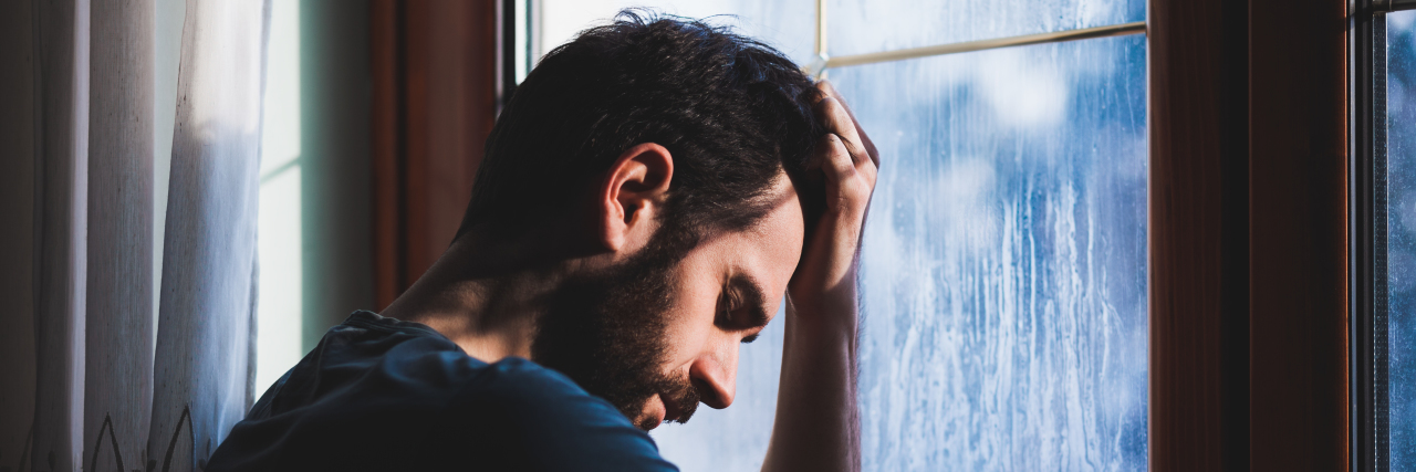 Sensory Overload and Sensory Fatigue Tired man sitting by the window.