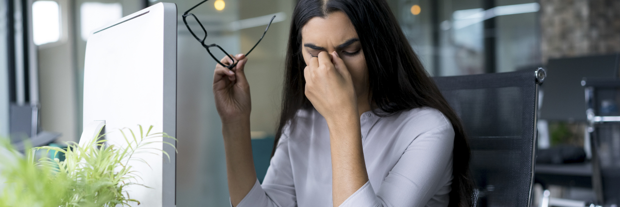 The Meaning of 'Fine' After Brain Injury Woman with headache at office.