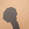 Shadow of someone holding an umbrella on the sand