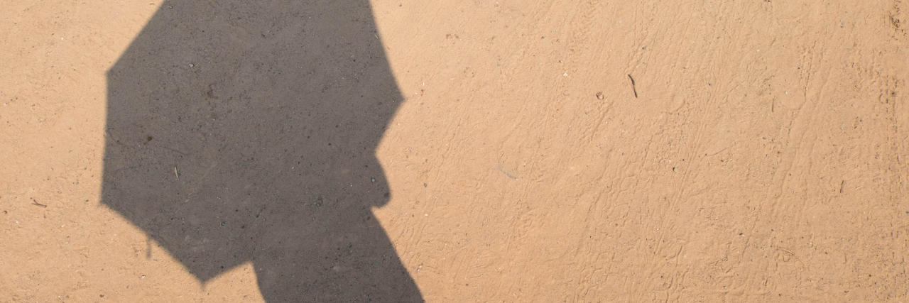 What It's Like to Live With Solar Urticaria Shadow of someone holding an umbrella on the sand