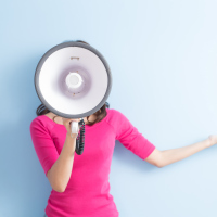 woman in a pink shirt holding up a megaphone