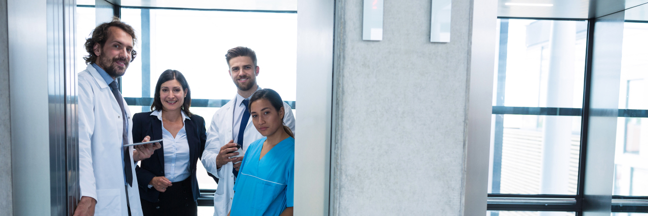Why Having the Right Doctor at Diagnosis Matters Doctors and businesswoman standing in elevator in hospital