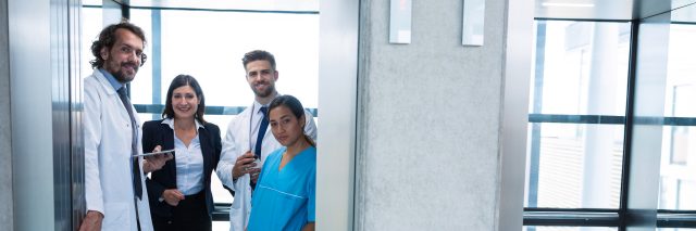 Doctors and businesswoman standing in elevator in hospital