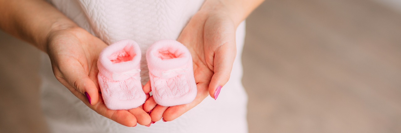 Please Don’t Make a Joke of Pregnancy This April Fool's Day Baby booties in the hands of a pregnant mother.